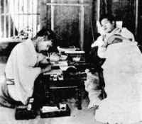 Onisaburo (right) dictating Reikai Monogatari to a scribe (left)